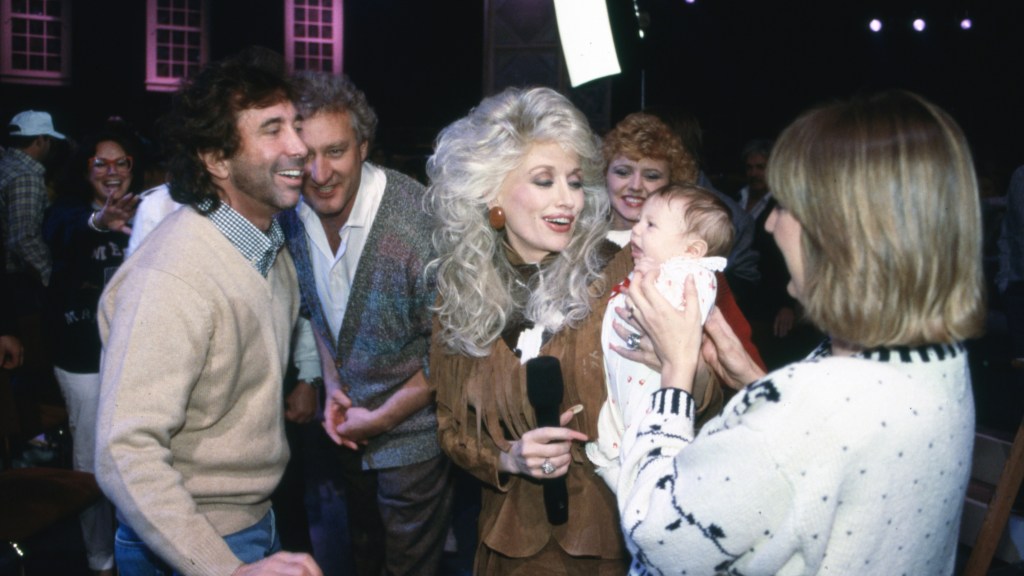 Dolly Parton being handed a baby
