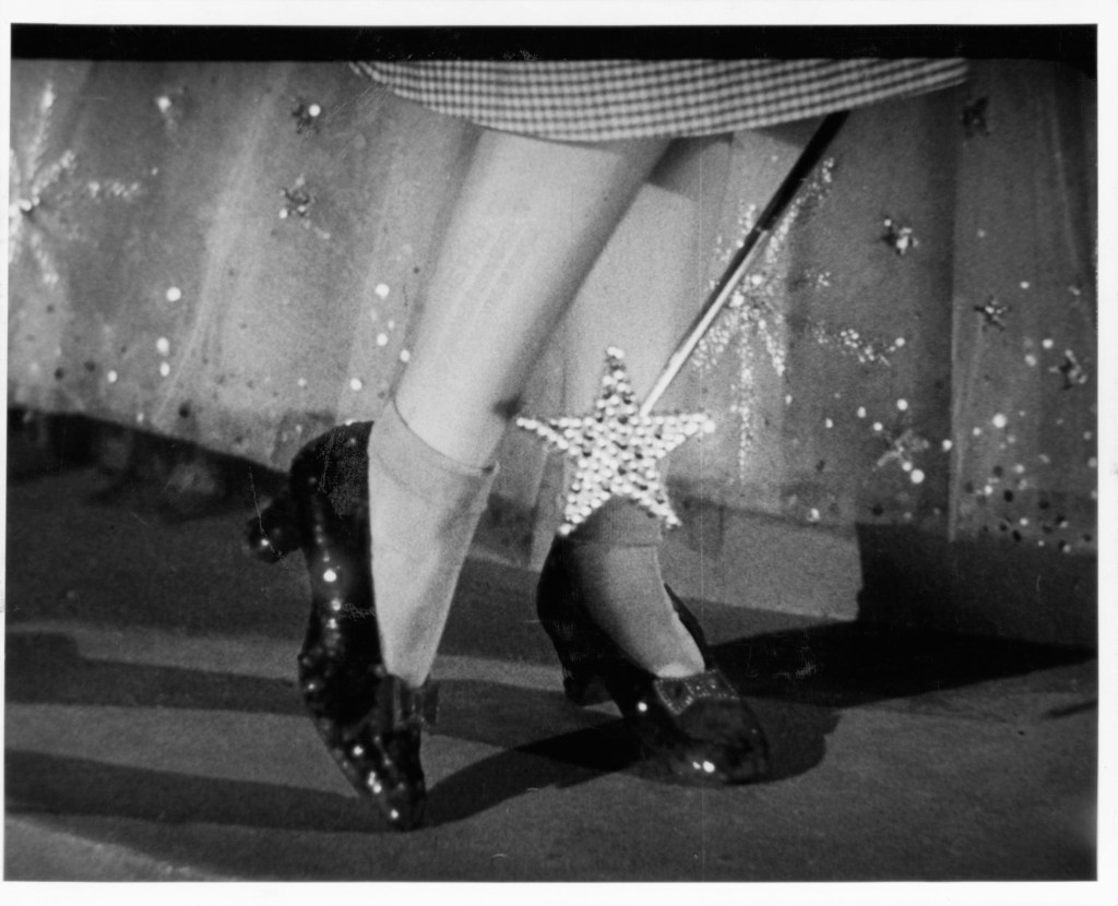 Close up of the ruby slippers on Judy Garland's feet with the tip of Glinda's wand in a scene from the film 'The Wizard Of Oz', 1939.