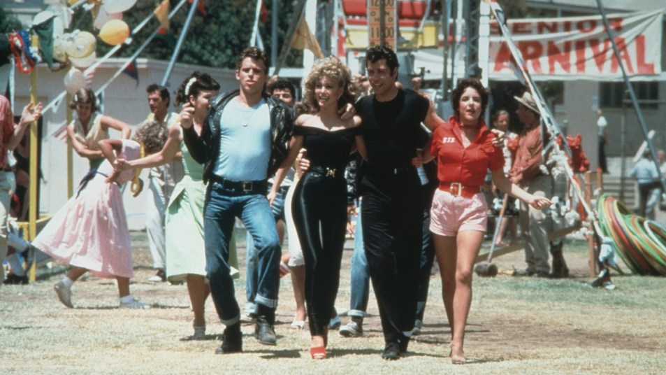 Left to right: actors Jeff Conaway, Olivia Newton-John, John Travolta and Stockard Channing walk arm in arm at a carnival in a still from the film, 'Grease' cast directed by Randal Kleiser.