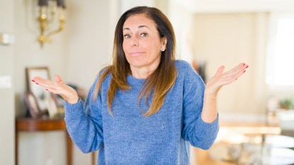 woman standing in her home shrugging, asking why is my house so dusty?