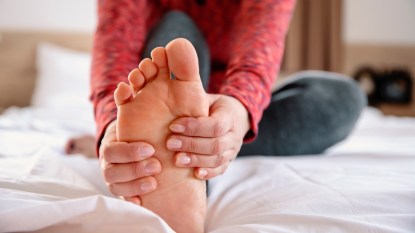 A woman holding her foot in bed as part of bunion self-care
