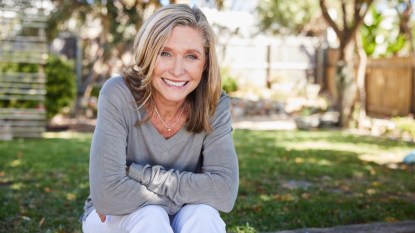 A mature woman with crossed arms while smiling outdoors practicing fibromyalgia self-care