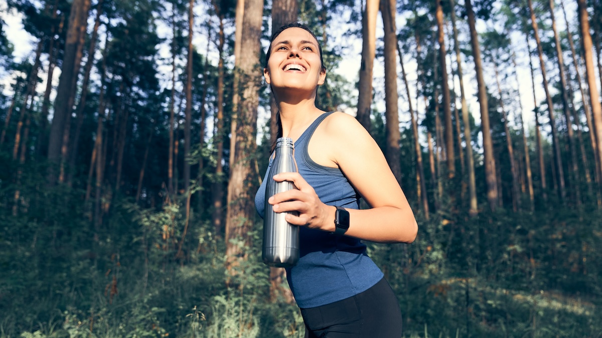 Woman exercising with water bottle in the woods