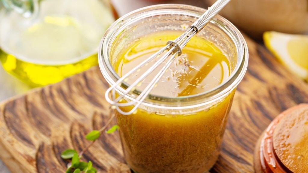 A glass jar of apple cider vinegar and olive oil salad dressing, which has benefits for women