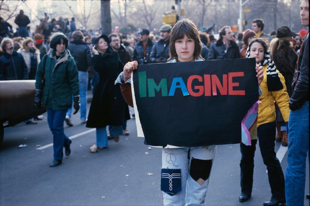 A young woman is holding a sign that says "Imagine" at a John Lennon vigil in New York City in December 1980: Beatlemania in My Life