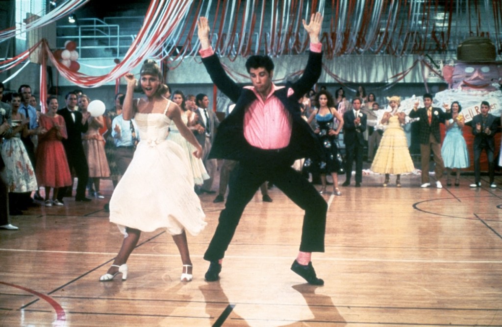 1978: Australian singer and actor Olivia Newton-John and American actor John Travolta dance in a crowded high school gym in a still from the film, 'Grease,' cast directed by Randal Kleiser.