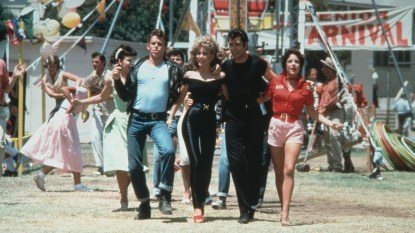 Left to right: actors Jeff Conaway, Olivia Newton-John, John Travolta and Stockard Channing walk arm in arm at a carnival in a still from the film, 'Grease' cast directed by Randal Kleiser.