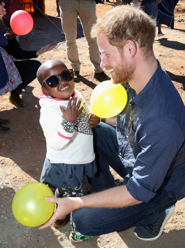 Prince Harry and little girl play with balloons