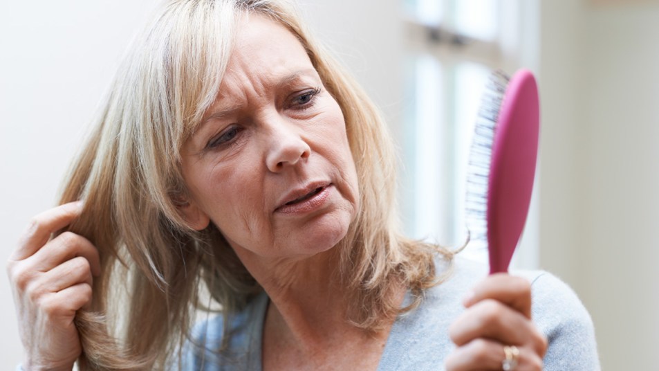 woman looking at her dirty hairbrush