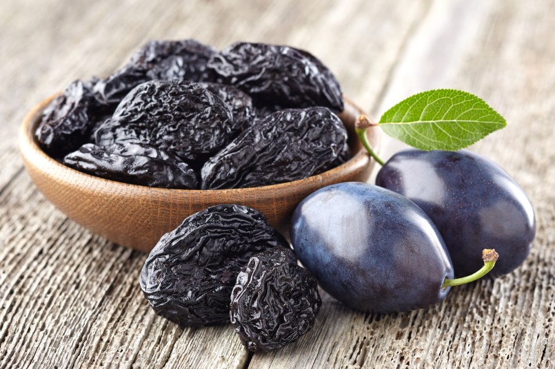 prunes in a wooden bowl on a table