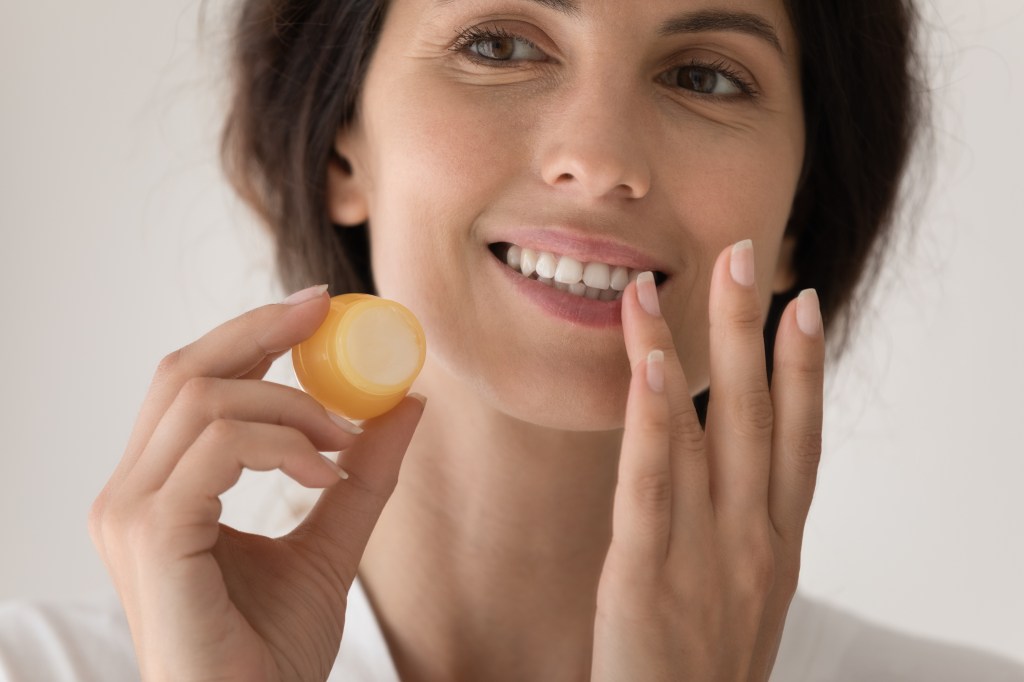 Woman applying a lip mask, one of the winter skin care routine steps