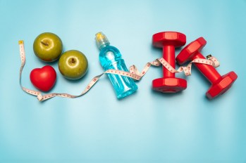 fruit, a water bottle, and weights on a blue background