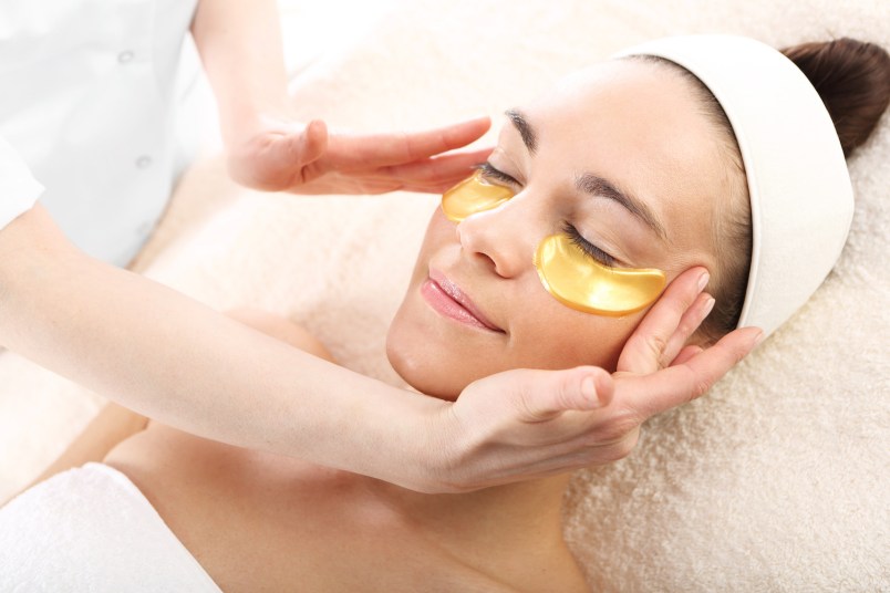 woman relaxing in a spa setting with gold under eye masks