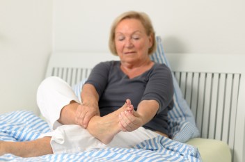 older woman holding painful foot