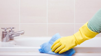 Gloved hand cleaning bathtub