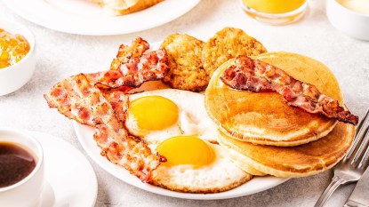 Breakfast plate with fried eggs, crispy bacon and pancakes
