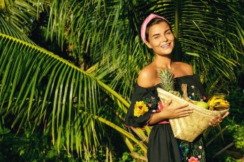 Happy young woman with a basket full of exotic fruits