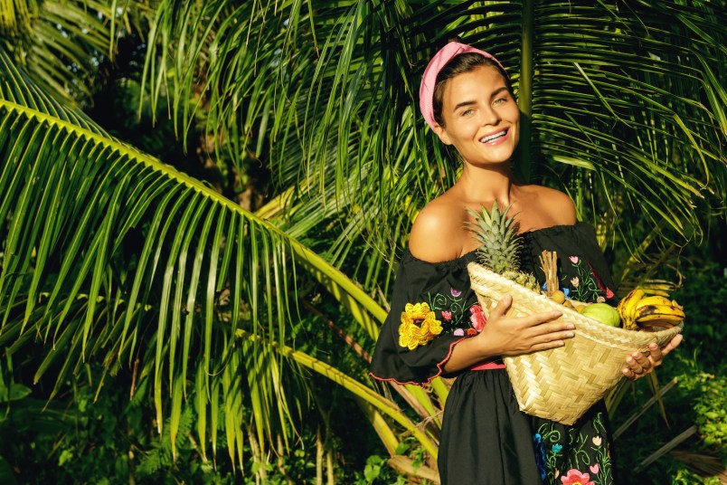 Happy young woman with a basket full of exotic fruits