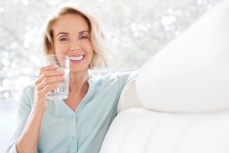 Mature woman smiling with glass of water.