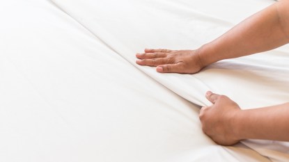 hands smoothing down bed sheets, concept for sanitizing sheets