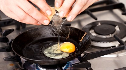 Hands cracking an egg into pan