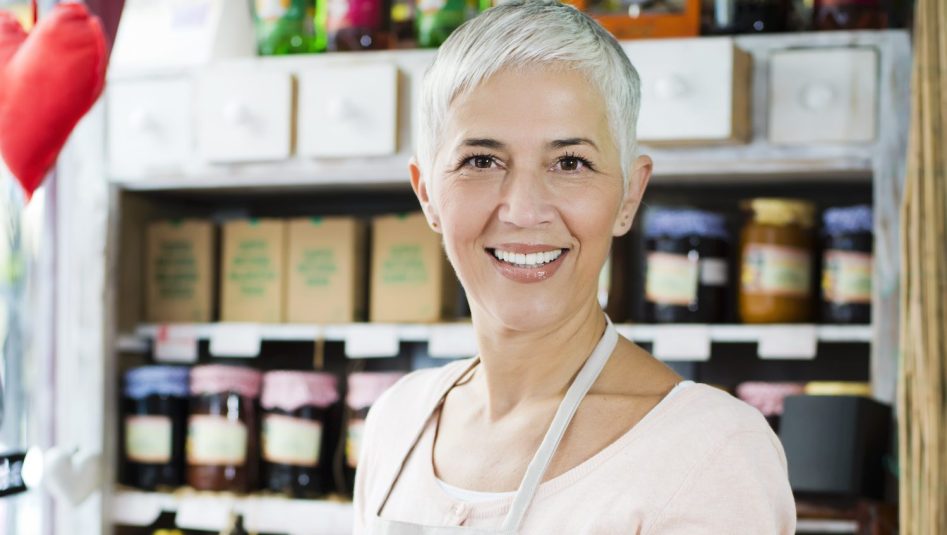 Mature woman holding homemade jam and juice at shop