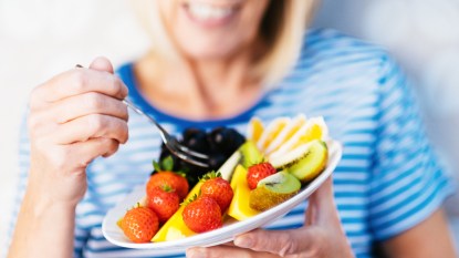 Woman eating plate of fruit