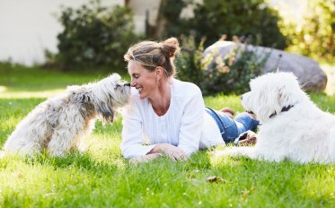 portrait of a mature content woman getting kisses from her dog in her garden
