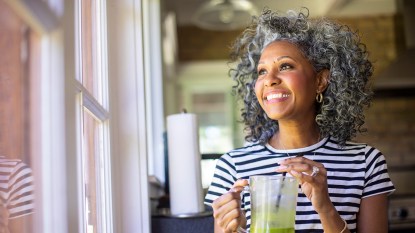 Black woman drinking a smoothie and smiling