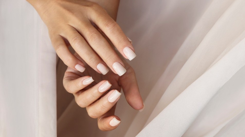 Natural nude acrylic nails on curtain background.