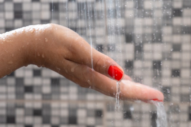 Womans hand testing shower water temperature