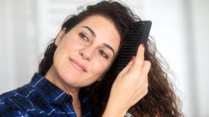 Woman combing her long, brown curly hair