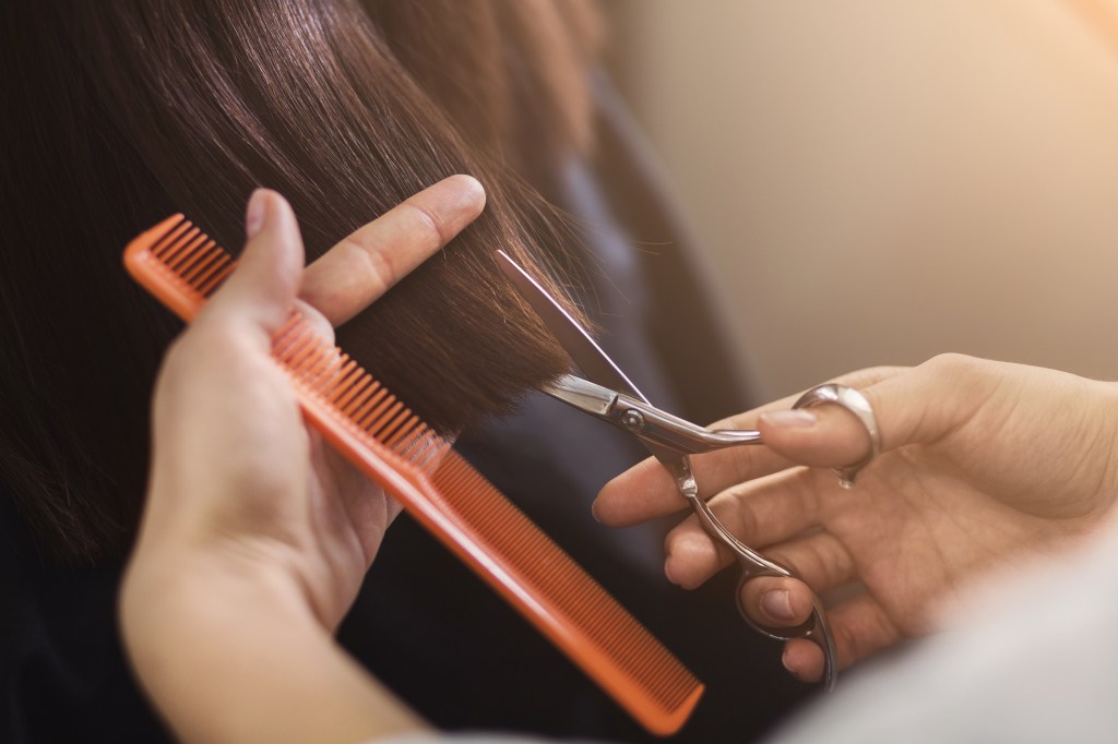 Woman getting her hair trimmed, which is one of the ways for how to prevent split ends