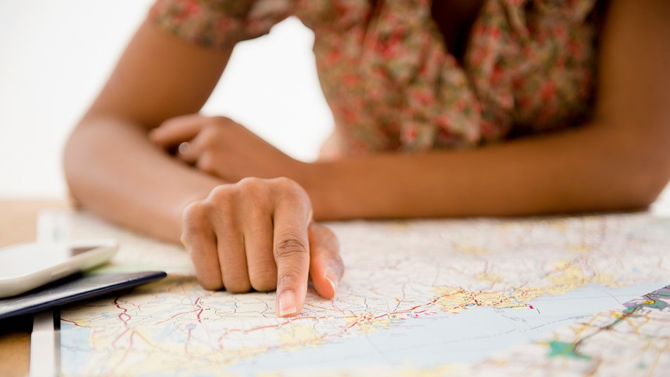 Woman's hand pointing to town on a map