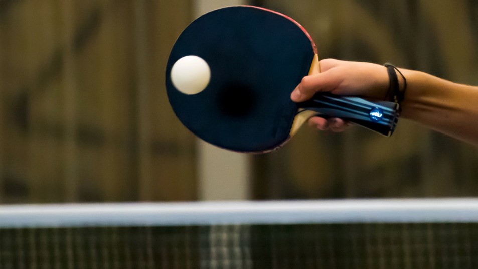 Woman's hand hitting ping pong ball with paddle