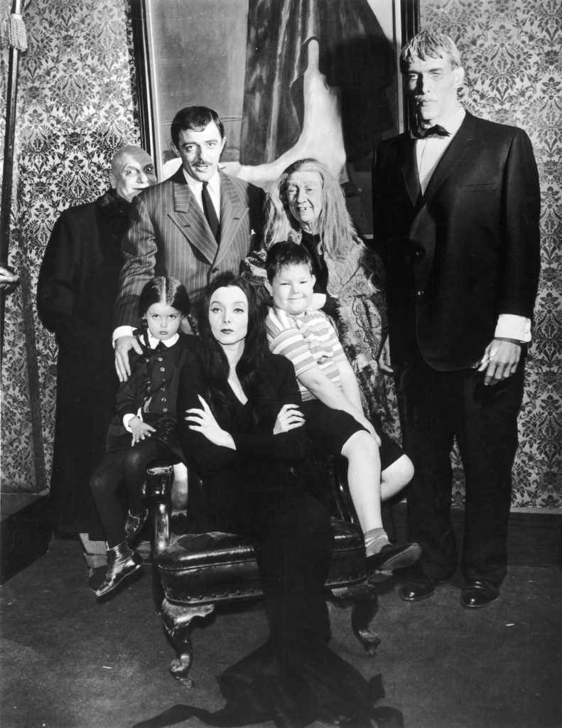 circa 1964: Group portrait of the cast of the television series, 'The Addams Family,' in costume. Standing (L-R): Jackie Coogan (1914 - 1984), John Astin, Blossom Rock, and Ted Cassidy. Sitting (L-R): Lisa Loring, Carolyn Jones, and Ken Weatherwax.
