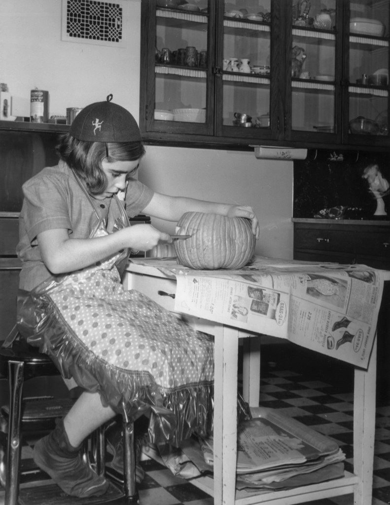 A young girl carving a pumpkin, 1955