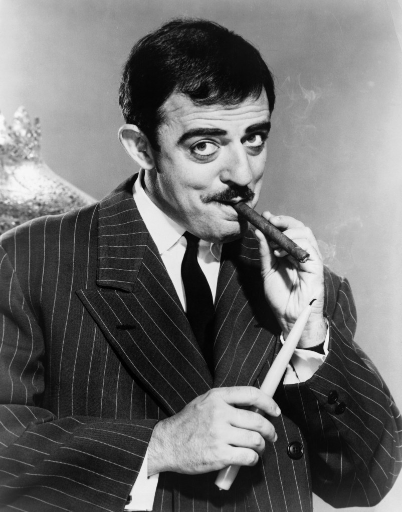 John Astin, who played the character Gomez Addams on the hit television show The Addams Family, uses a candle to light his cigar.