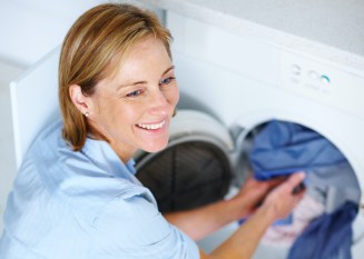 Smiling mature woman doing laundry at home
