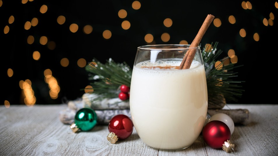 Glass of eggnog with cinnamon stick and Christmas ornaments