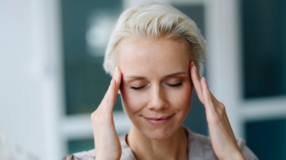 A woman with short hair pressing her temples as one of the top sinus pressure relief points