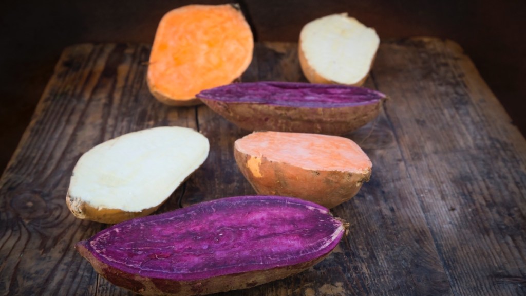 Orange and purple sweet potatoes beside white potatoes