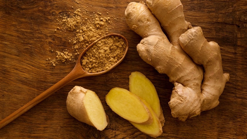Whole ginger root next to ground ginger in a spoon, one of the most popular holiday spices