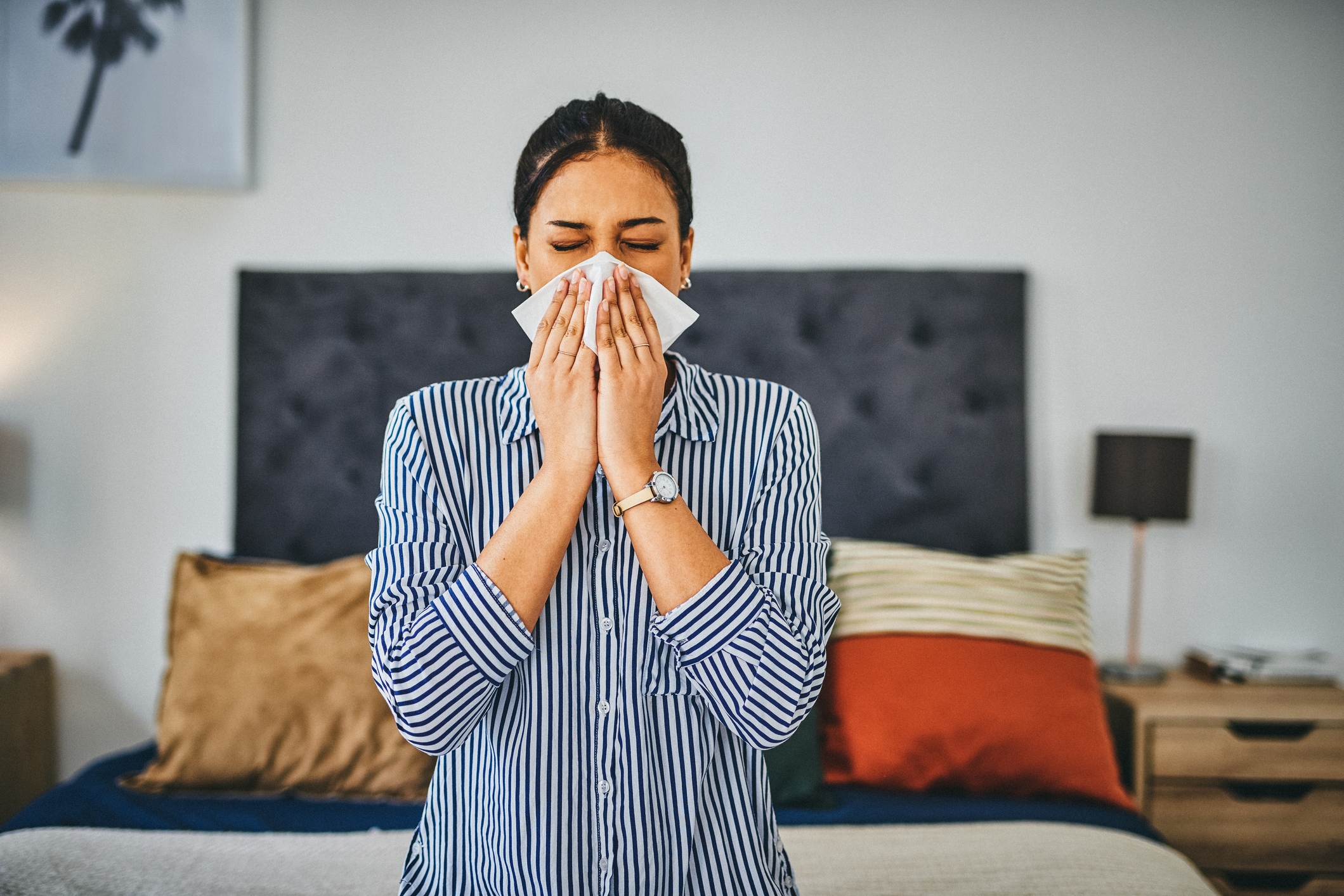 woman with stuffy nose sneezing into tissue