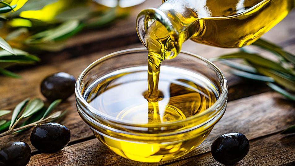 Pouring extra virgin olive oil from a bottle to a glass container