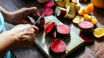 Hands slicing beets with a knife
