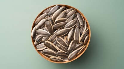 A bowl of sunflower seeds on a green background, which has benefits for females