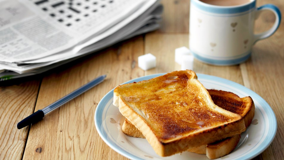Plate of toast next to coffee and newspaper