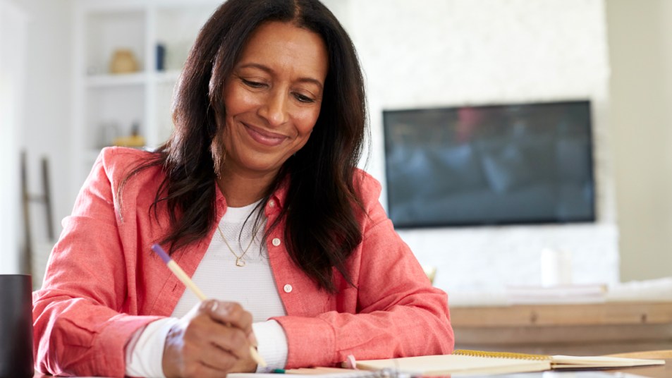 Woman smiling and writing on pad of paper