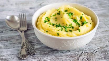 Bowl of mashed potatoes with spoon and fork